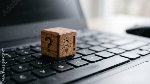 wooden block with question and idea icons on a black laptop keyboard