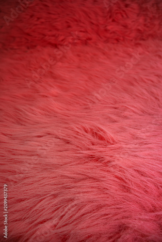 Bright red rug with long fibers spread across a wooden floor in a room