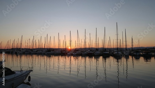 Sailboats Docked in a Harbor With a Sunset Over the Water in the Evening