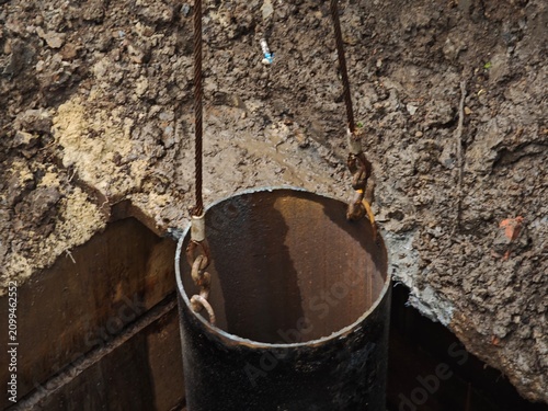 Obraz na plátne Detailed view of industrial metal utility pipe rim attached to heavy steel hooks and wire rope slings during underground pipeline installation