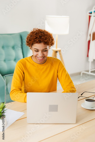 African American girl using laptop at home office looking at screen typing chatting reading writing email. Young woman having virtual meeting online chat video call conference. Work learning from home