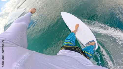 FPV, POV: Surfer glides along a turquoise wave at a tropical surf spot in the remote Mentawai Islands. Young man enjoys riding his white surfboard and makes splashing turns on a playful glassy wave.