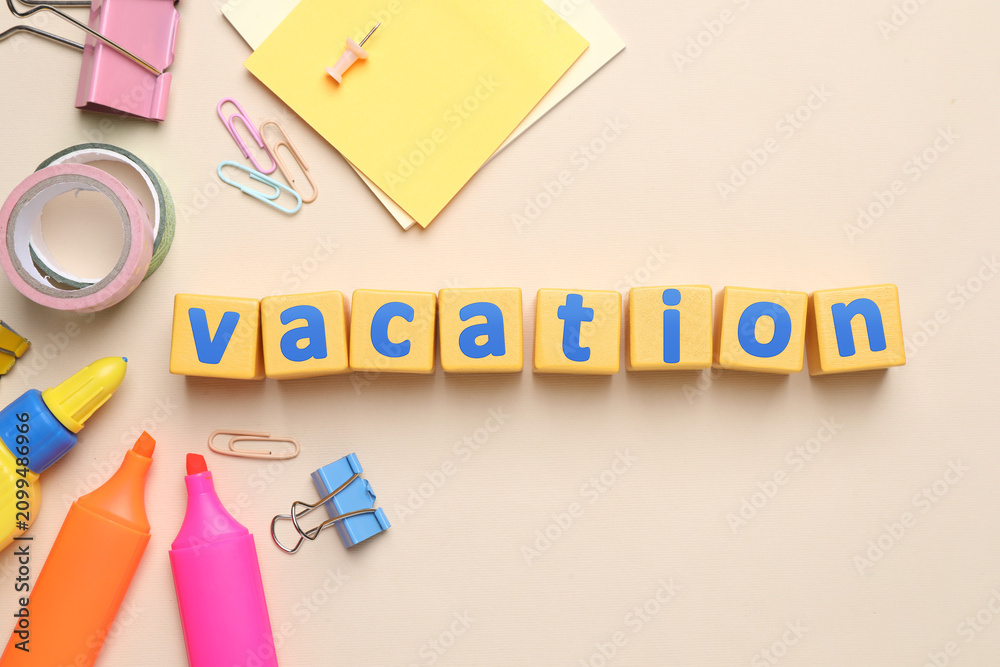 Obraz premium School holiday. Wooden cubes with word Vacation and stationery on beige background, flat lay