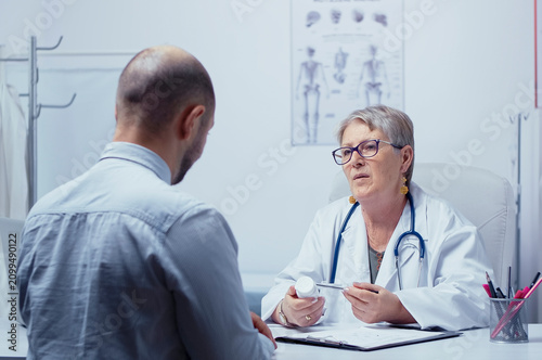 Quadro su tela Authentic elderly experienced woman doctor talking about pills dosage with male patient