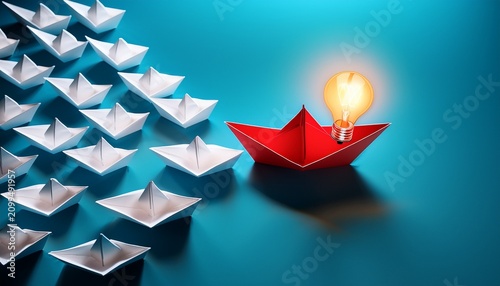 red paper boat carrying glowing light bulb standing out among white paper ships representing unique leadership vision and innovative thinking in competitive business market