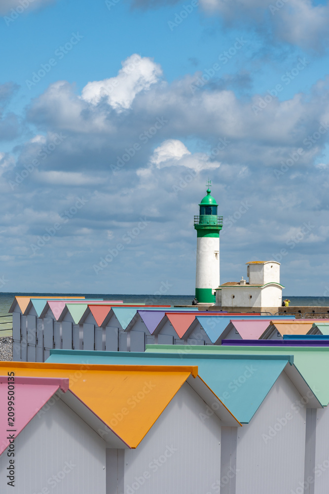Fototapeta premium Views of ocean beach and colourful beach huts or cabins in Le Treport, seaside resort in Normandy, France, with white cliffs along English Channel, travel destination in France