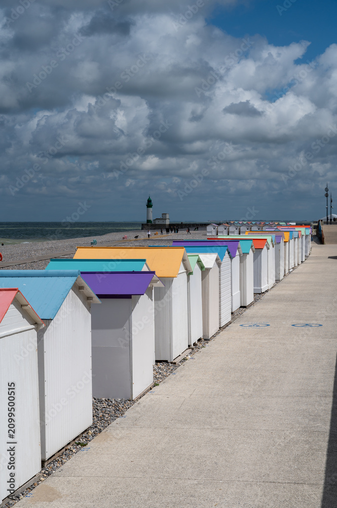 Fototapeta premium Views of ocean beach and colourful beach huts or cabins in Le Treport, seaside resort in Normandy, France, with white cliffs along English Channel, travel destination in France