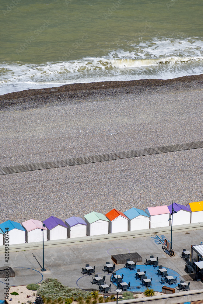 Fototapeta premium Views of ocean beach and colourful beach huts or cabins in Le Treport, seaside resort in Normandy, France, with white cliffs along English Channel, travel destination in France