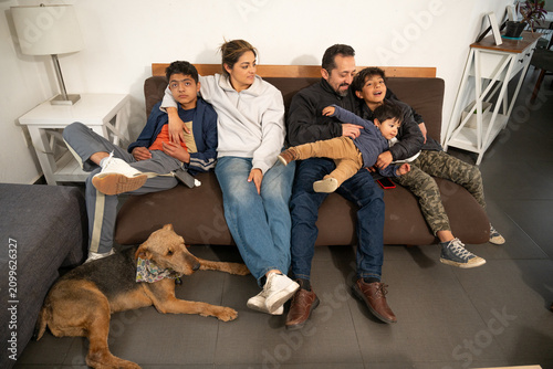 Canvas Print Playful Hispanic family laughing and tickling baby boy on the couch