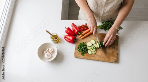 An overhead view of a person preparing a fresh, healthy meal, chopping vegetables in a bright, clean kitchen.