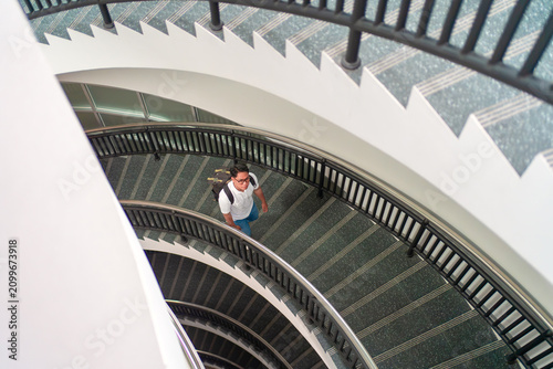 Young Professional Walking Up Spiral Staircase in Modern Building