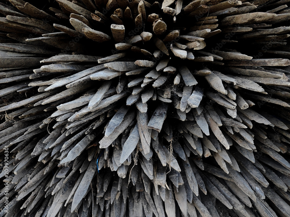 Naklejka premium close-up view of a tightly stacked bundle of sharpened wooden stakes, highlighting the rugged texture, weathered wood grain, and radial arrangement. The image creates a striking abstract pattern