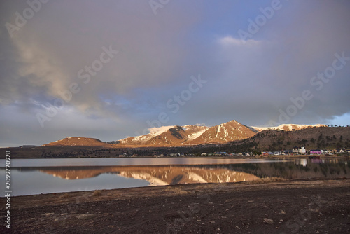 Winter landscape in Caviahue, Neuquen, Argentina. The mountains, bathed in morning light, are reflected on the surface of the lake.