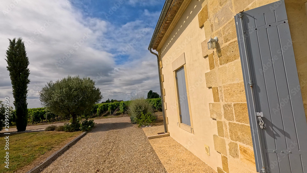Obraz premium Stone Winery Building Overlooking Lush Green Vineyards in Bordeaux France
