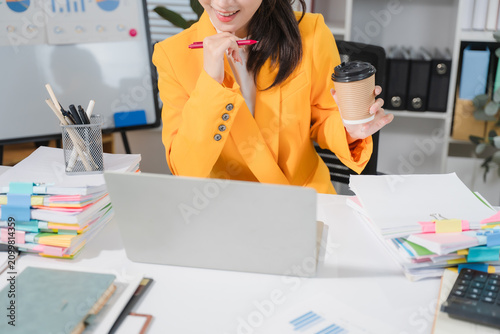 Cuadro en lienzo Creative Professional Working Remotely: A focused woman in a vibrant yellow blazer works diligently at her desk, surrounded by stacks of documents and a laptop, holding a pen and a coffee cup