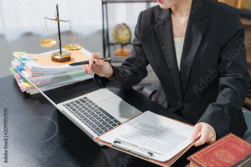 Legal Professional at Work: A dedicated legal professional, dressed in a formal suit, meticulously reviews documents and works on a laptop in a law office setting.