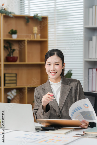 Cheerful business lady working on laptop in office, Asian happy beautiful businesswoman in formal suit work in workplace.