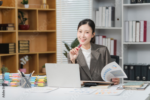 Cheerful business lady working on laptop in office, Asian happy beautiful businesswoman in formal suit work in workplace.