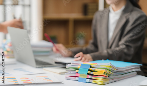 Businessman man working in stacks of papers searching for unfinished paperwork information on form check stack on table and checking financial papers in busy workload