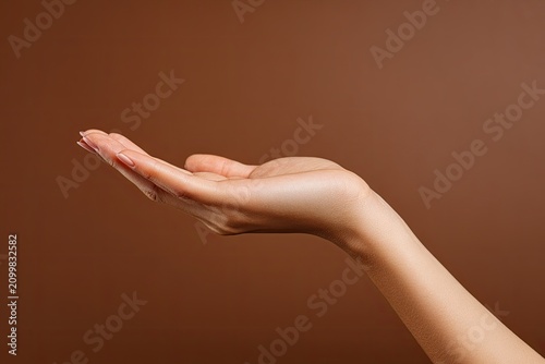 Woman Hand Open Palm Offering Something Against Brown Background