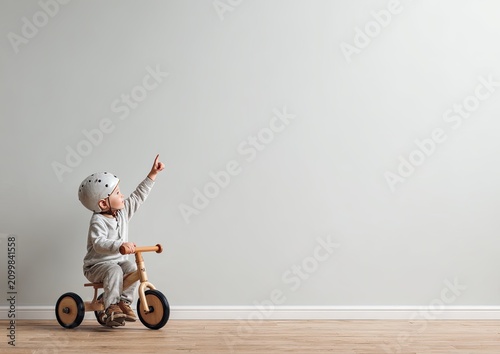 Child in Helmet Rides Tricycle Pointing Up Toward Copy Space
