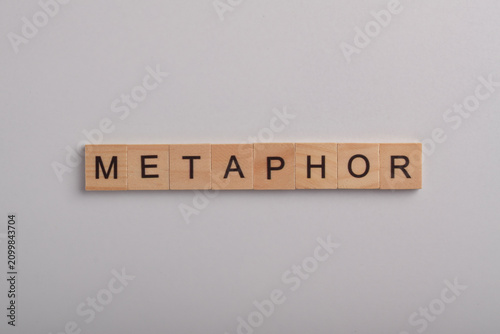 Foto Wooden letter blocks spelling metaphor on a white background, representing figurative language, literature, creative writing, communication, education, and language learning