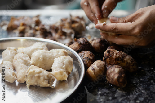 Indian female hands peeling boiled taro root for cooking