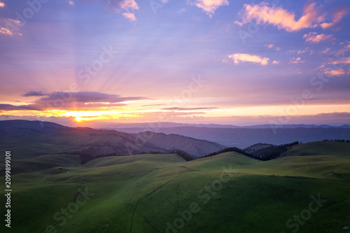 Obraz na płótnie Dramatic sunset over Karakul grassland with rolling green hills and colorful sky