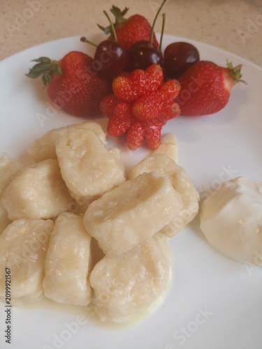 Fresh lazy cottage cheese dumplings with seasonal berries on a white plate. Soft homemade lazy cottage cheese dumplings accompanied by fresh summer berries including strawberries, raspberries