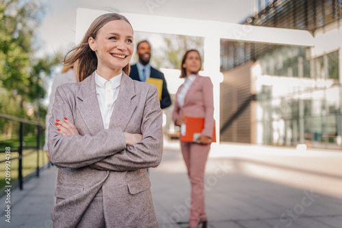 Foto Confident businesswoman smiling with business team outdoors