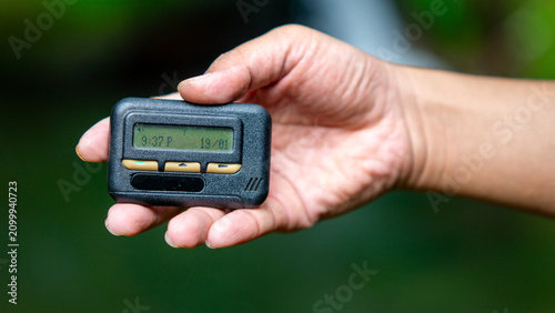 Hand holding pager beeper device, retro phone 90s instant communication and connection, sms messaging in the early 80s 90s digital age