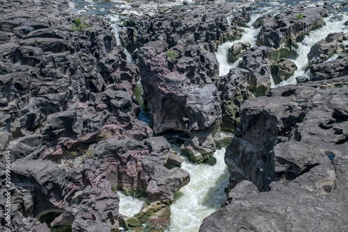 A high-angle shot of the naturally formed basalt rock potholes, locally known as Ranjan Khalge, carved over centuries by the Kukadi River in Nighoj, Ahmednagar district, Maharashtra, India.