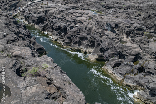 A high-angle shot of the naturally formed basalt rock potholes, locally known as Ranjan Khalge, carved over centuries by the Kukadi River in Nighoj, Ahmednagar district, Maharashtra, India.
