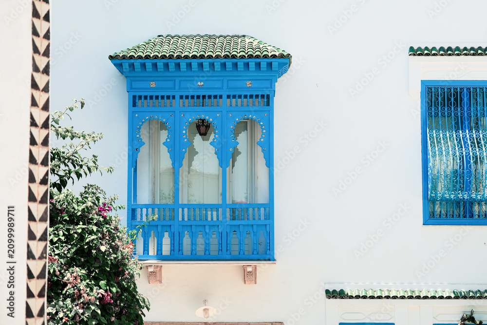 Fototapeta premium White Building with Blue Shutters and Bougainvillea in Mediterranean Town
