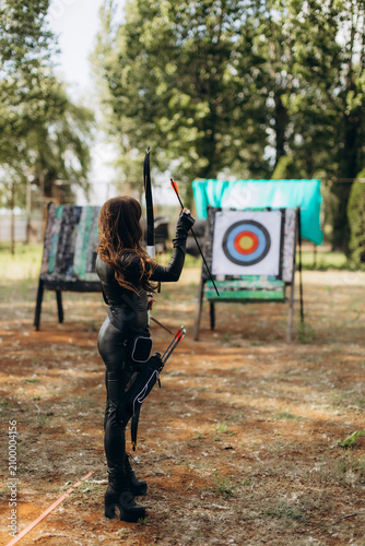 Fotografie Woman preparing to shoot arrow during archery practice