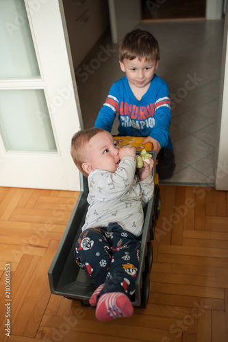 Fotografía Cheerful young boy gives his little brother a fun ride in a toy dump truck acros