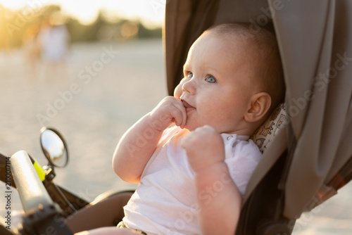 Foto Adorable baby with blue eyes looking out from a stroller during golden hour