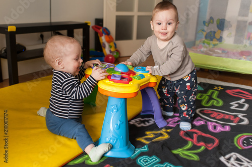Canvastavla Cheerful twin brothers joyfully explore a musical activity table, learning to st