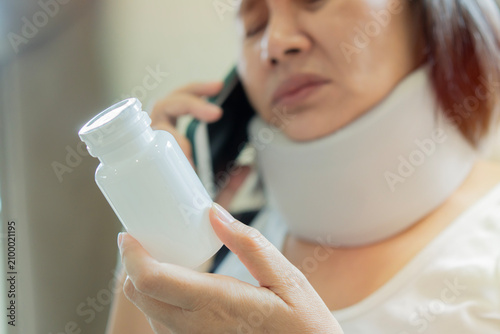 Bild auf Leinwand A stressed and sick middle-aged female patient in a soft collar brace, looking a