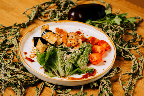 Konstfotografi Roasted eggplant slices served with fresh green salad and cherry tomatoes on a w