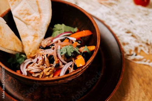 Healthy bowl of shredded chicken with black beans and fresh vegetables served during lunch