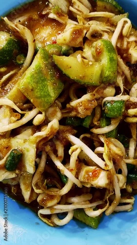 Savory Indonesian stir-fried noodles with vegetables and bean sprouts are served on a blue plate.