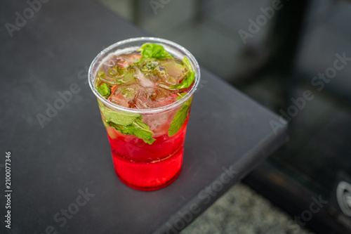 Fresh strawberry lemonade with mint and ice. Refreshing strawberry lemonade served with fresh mint leaves and ice cubes in a transparent plastic cup. Cold summer drink concept.