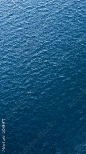 A deep blue water surface with gentle rolling ripples, vertical 9:16 full-frame overhead view.