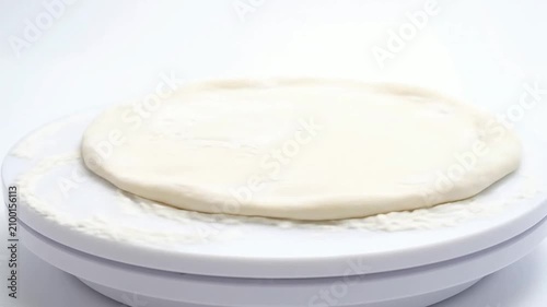 Freshly Prepared Pizza Dough on Rotating Platform with Smooth Texture Against Plain White Background Ideal for Culinary and Baking Visuals