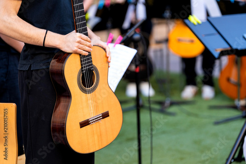 Musician holding an acoustic guitar, preparing for an outdoor concert performance
