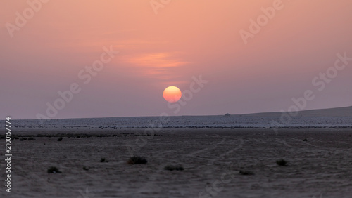 Konstfotografi Beautiful pink and purple sunset dipping below a flat desert horizon, creating a serene, minimalist twilight landscape under pastel skies