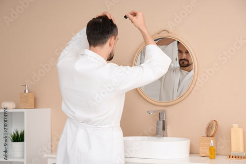 Handsome man applying serum...