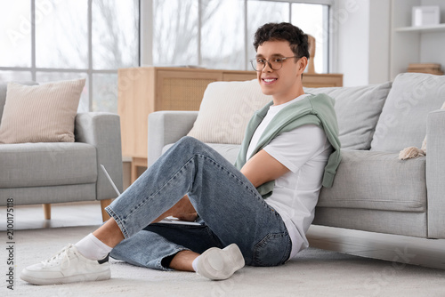 Young man working with laptop on floor at home