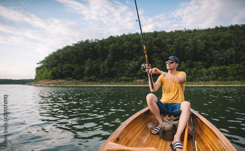 Man fishing from wooden canoe, copy space